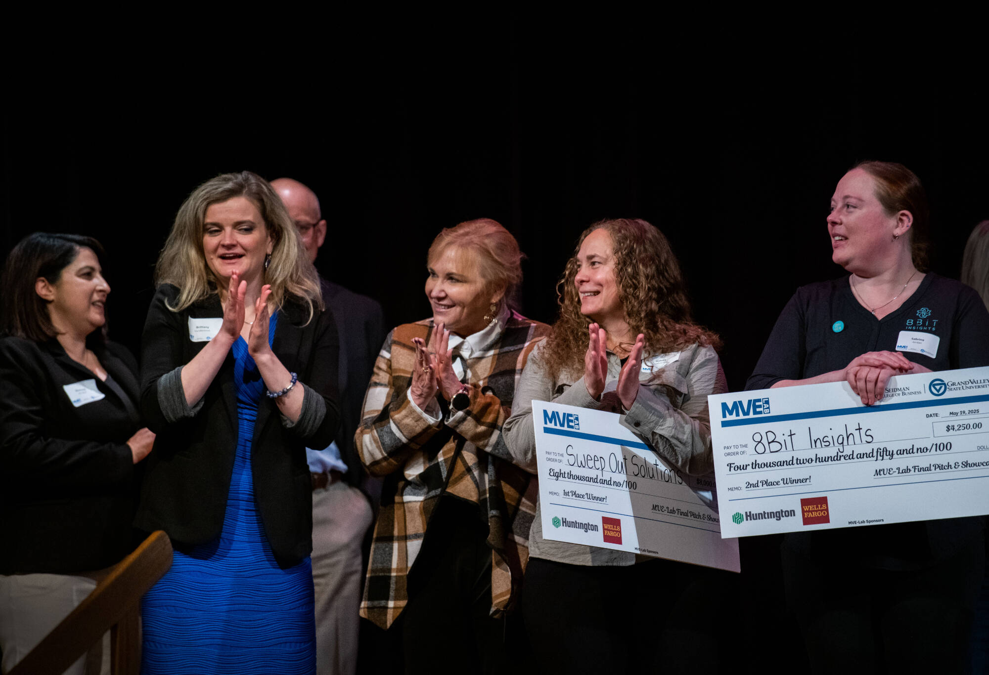 At far left are Shorouq Almallah and Brittany VanderBeek. MVE-Lab participants Hahna Martinez and Sabrina Jordan are at the right, holding checks for winning part of the prize money at the pitch competition May 19 at the Traverse City Opera House.